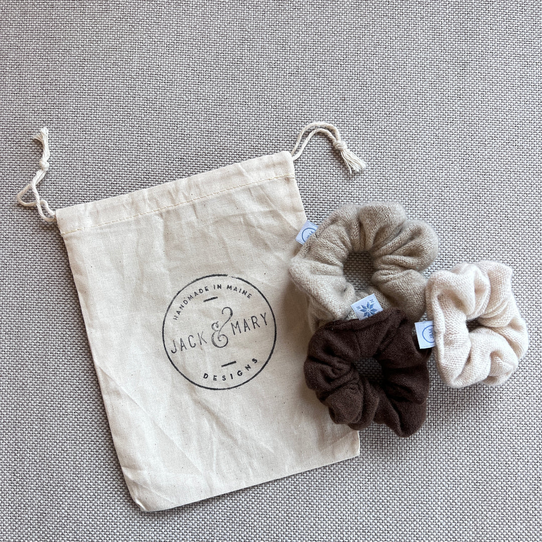 A set of three cashmere scrunchies with a drawstring canvas logo bag.